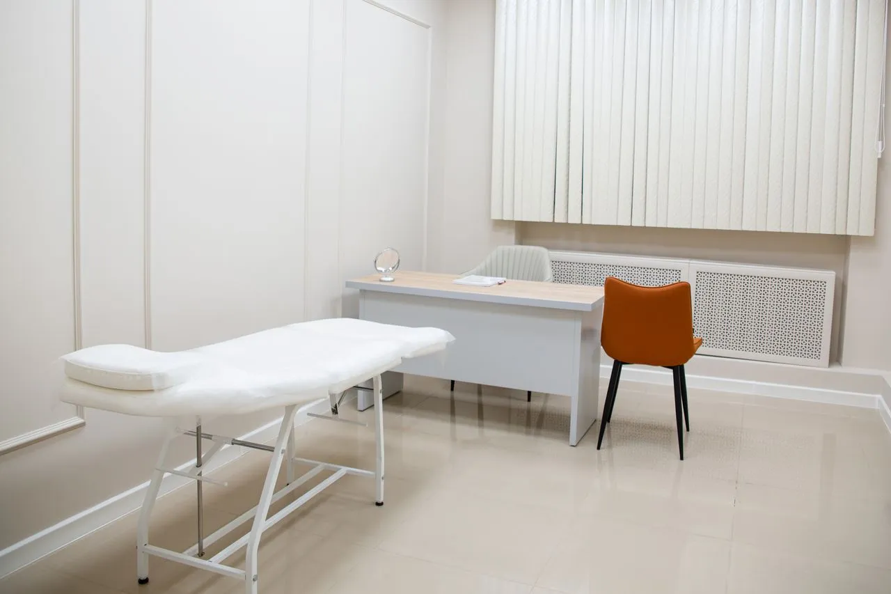 Clean consultation room with a treatment couch and desk