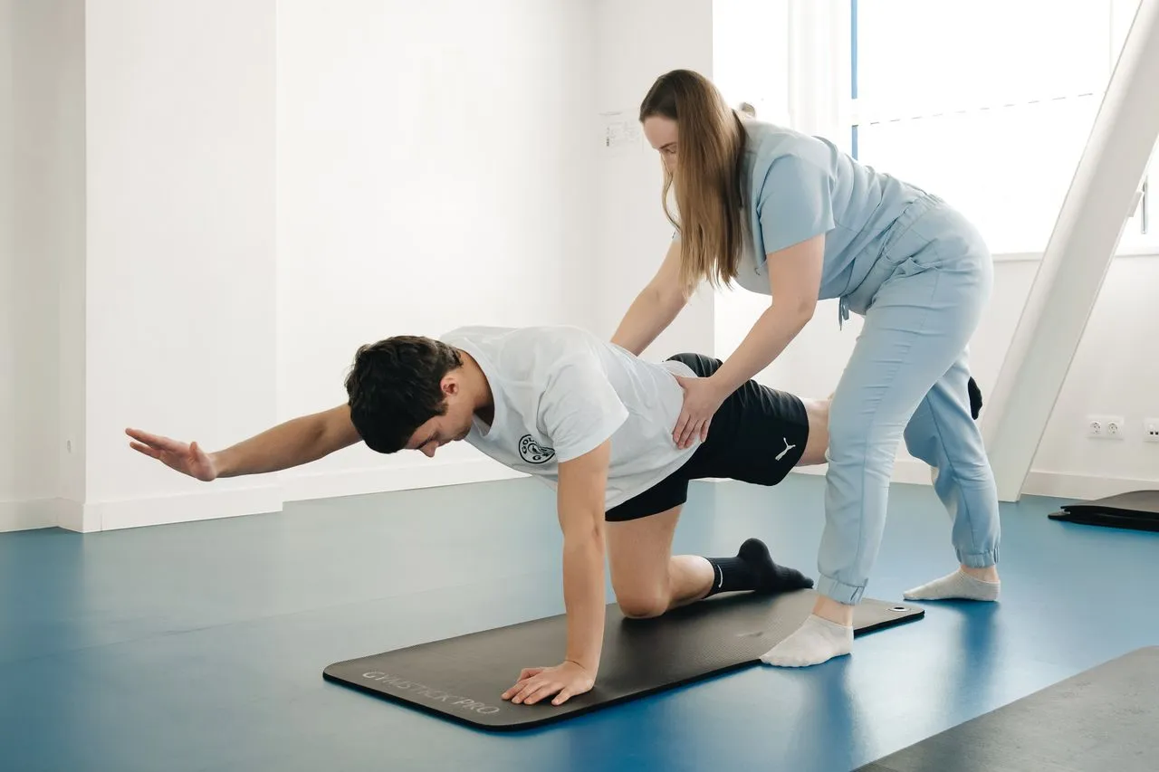 Physiotherapist guiding a patient through a floor-based balance exercise