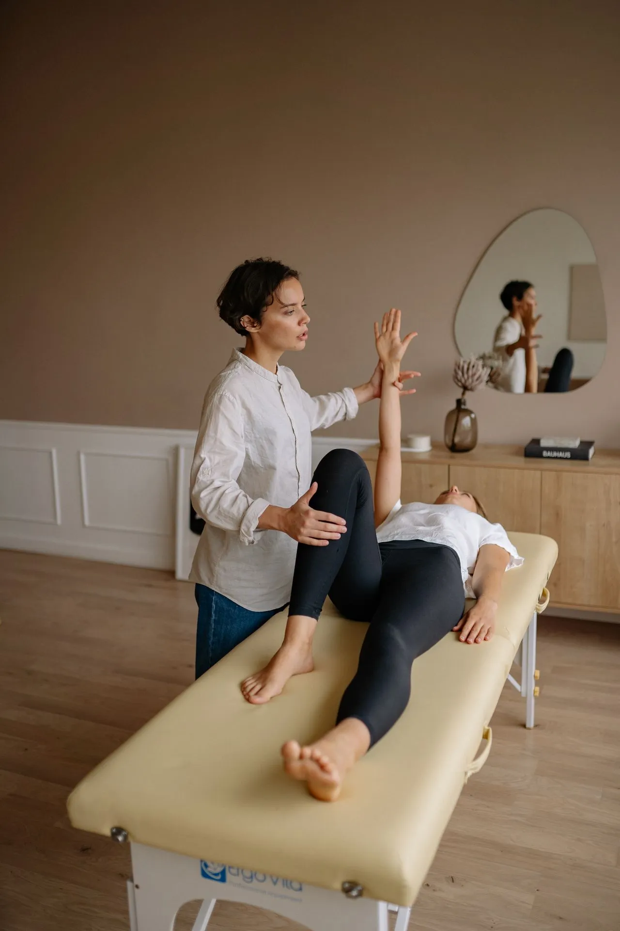 Therapist mobilising a patient’s hip on a treatment bed