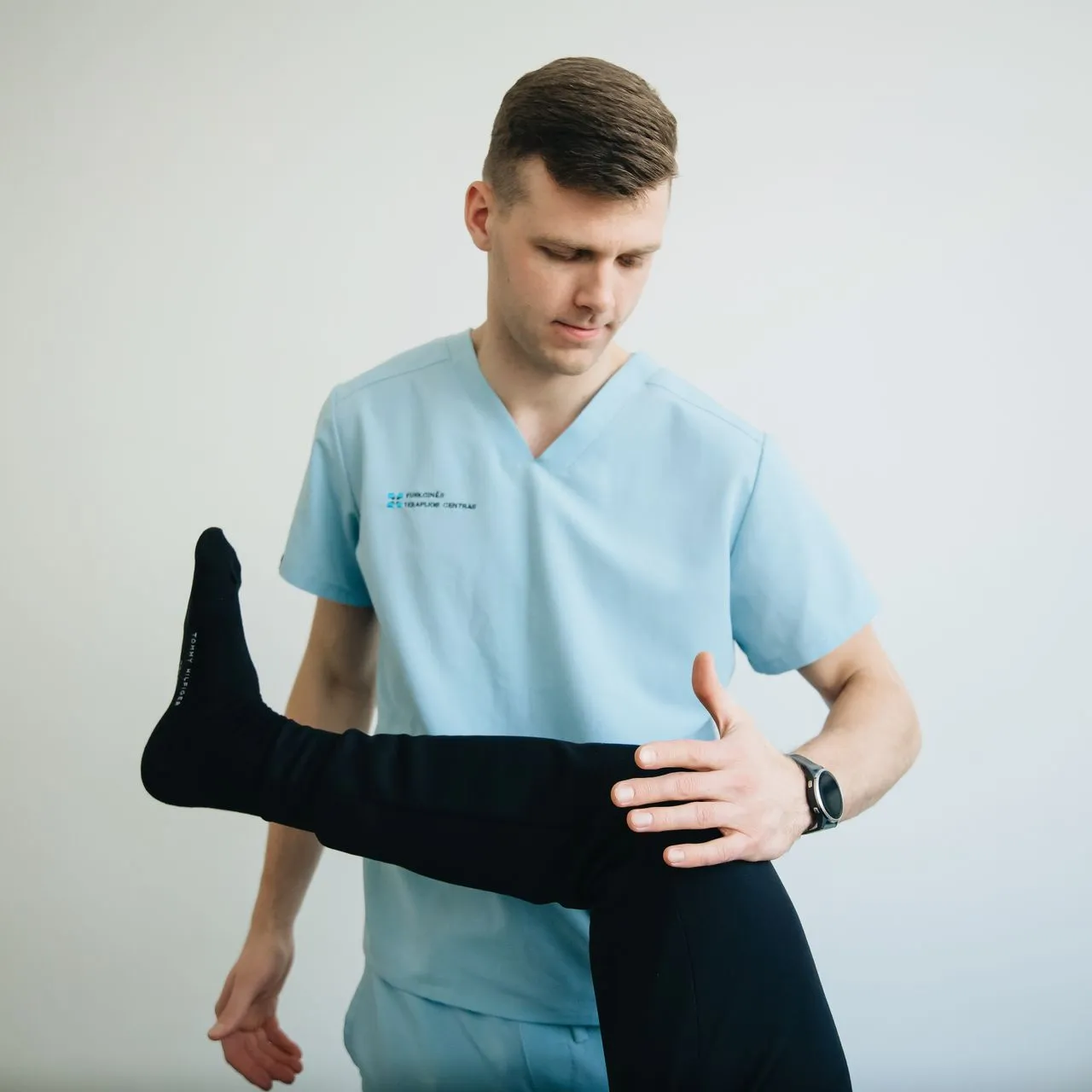 Physiotherapist supporting a patient’s leg during a knee assessment