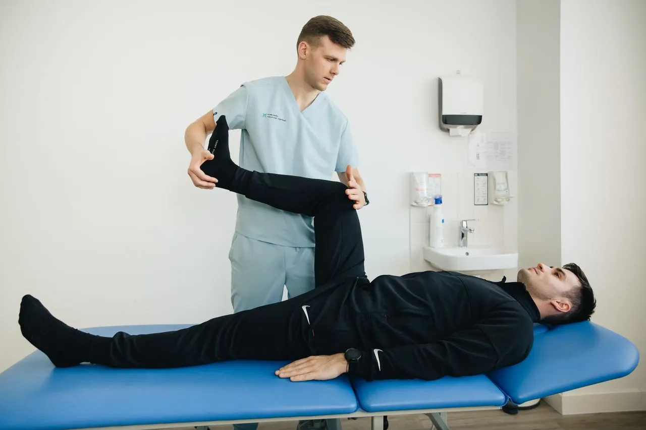 Physiotherapist lifting a patient’s leg on a treatment table